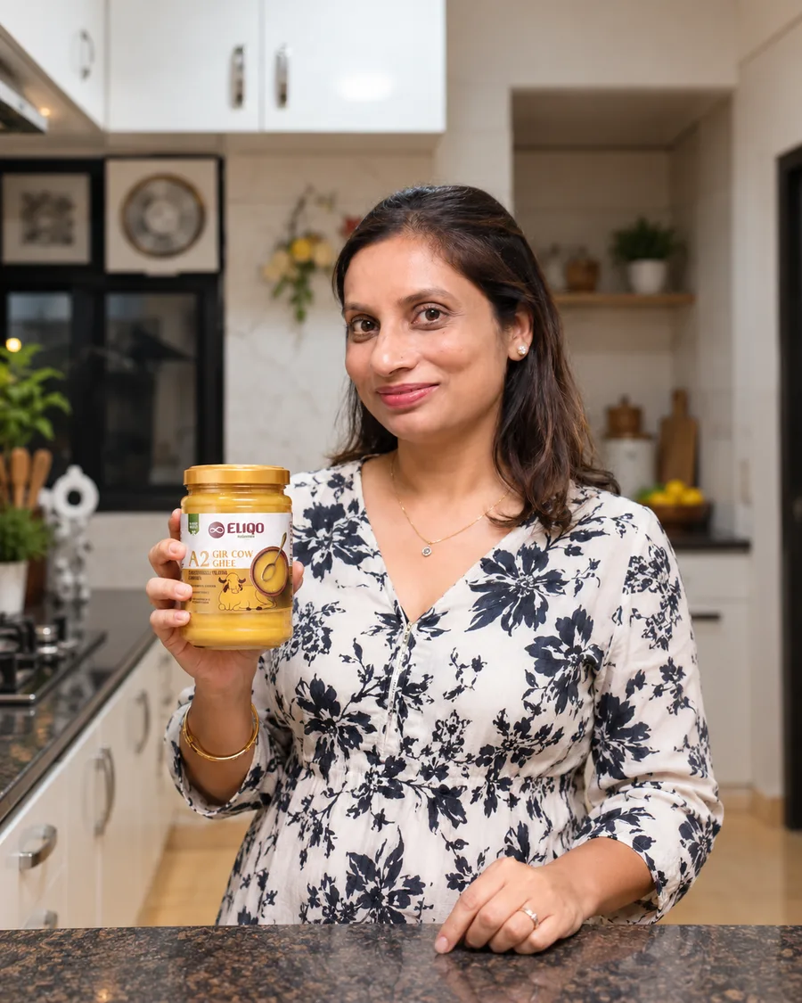 A customer holding a jar of Eliqo A2 Gir Cow Ghee in her kitchen
